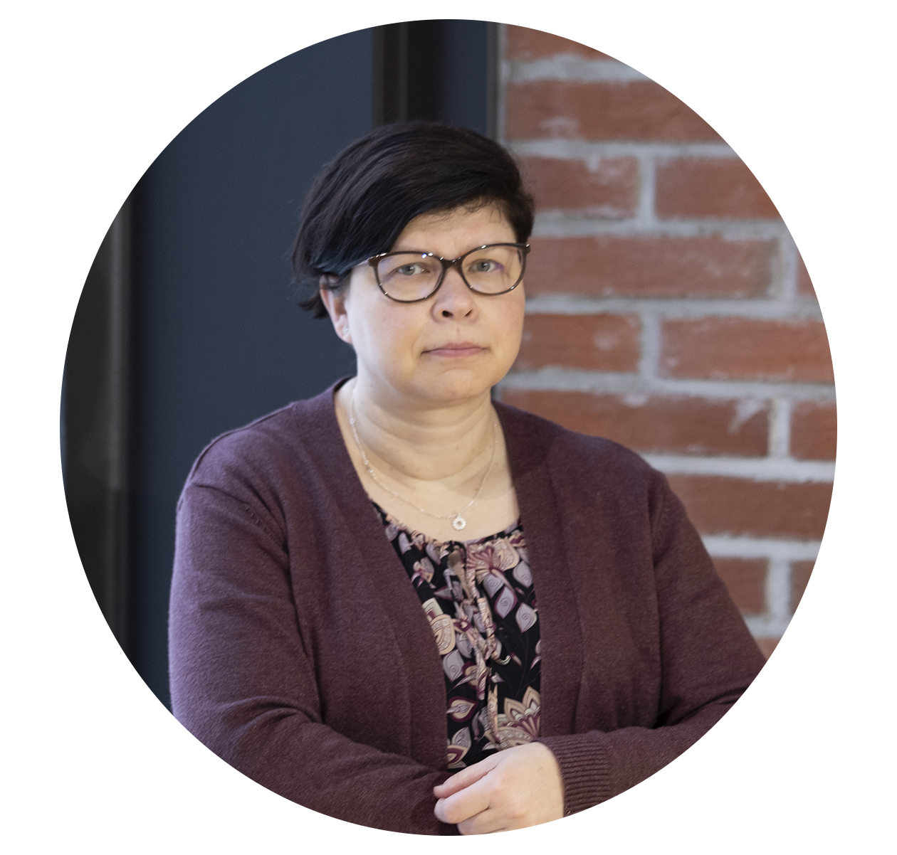 Kirsti Cura, taustalla tiiliseinä.